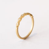A slender yellow gold wedding band featuring carved diamond shapes across the top set with tiny diamonds and edged with milgrain beading.