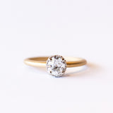 A yellow gold solitaire engagement ring with a white gold center head featuring an old European cut diamond. The sides of the center basket are set with tiny diamonds in milgrain details.