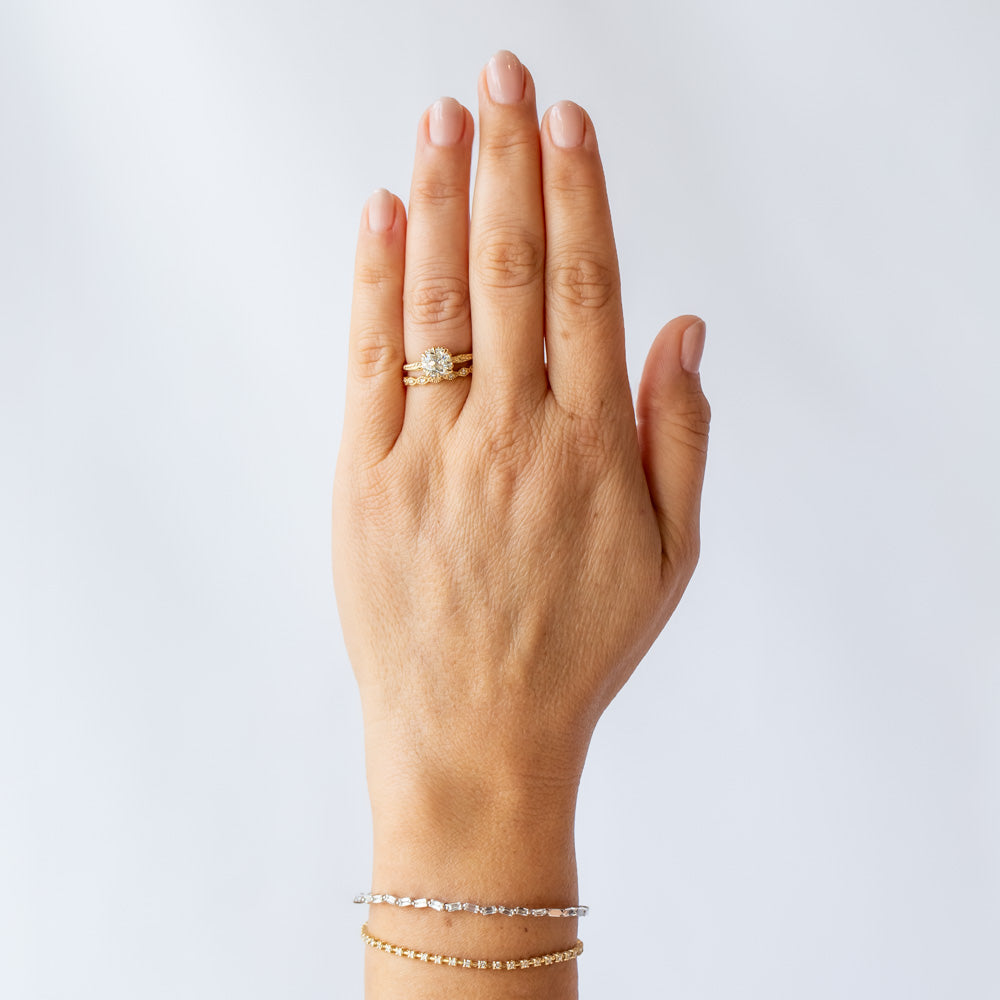 A yellow gold solitaire engagement ring with an old Eurpoean cut diamond and delicate leaf accents on the slender band. On hand.