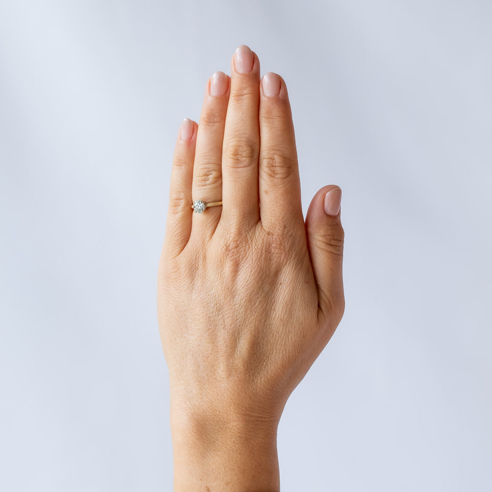 A yellow gold solitaire engagement ring with a white gold center head featuring an old European cut diamond. The sides of the center basket are set with tiny diamonds in milgrain details.