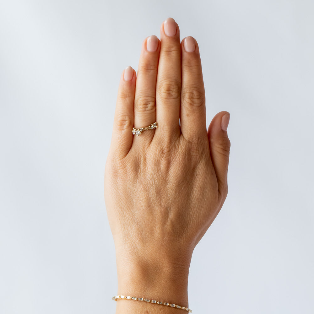 A textured gold band set with asymmetric clusters of small diamonds. On hand.