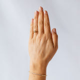 A round diamond solitaire engagement ring set in a granulated setting in yellow gold. On hand.