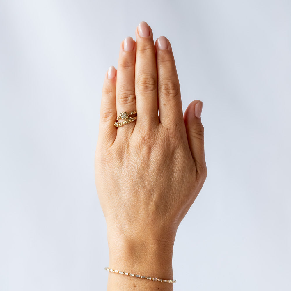 A round diamond solitaire engagement ring set in a granulated setting in yellow gold. On hand.