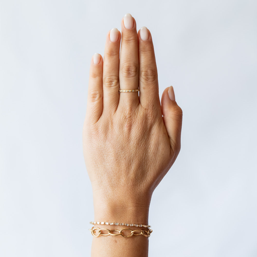 A textured yellow gold wedding band with flush set diamonds all the way around. On hand.