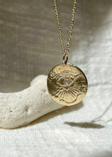 Carved yellow gold medallion necklace with an eye, a diamond at its center, from Communion by Joy.