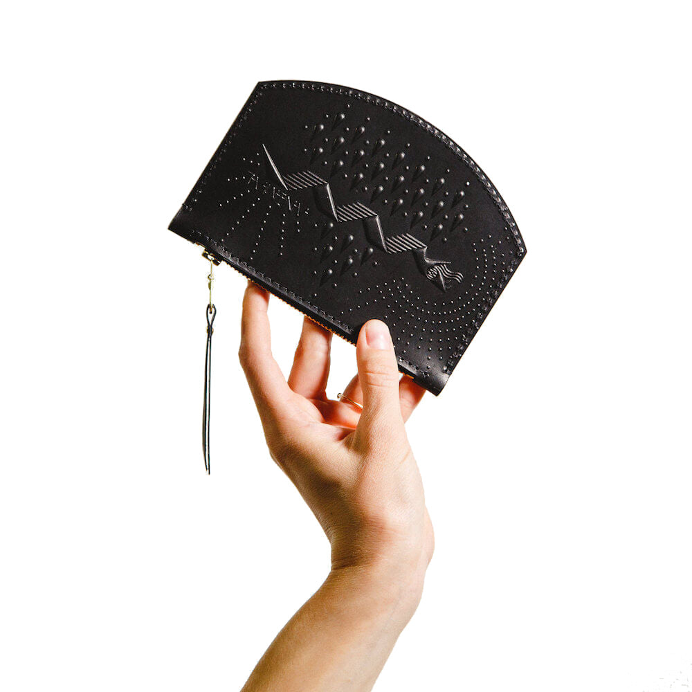Black leather coin pouch with hand stamped snake design, shown in hand