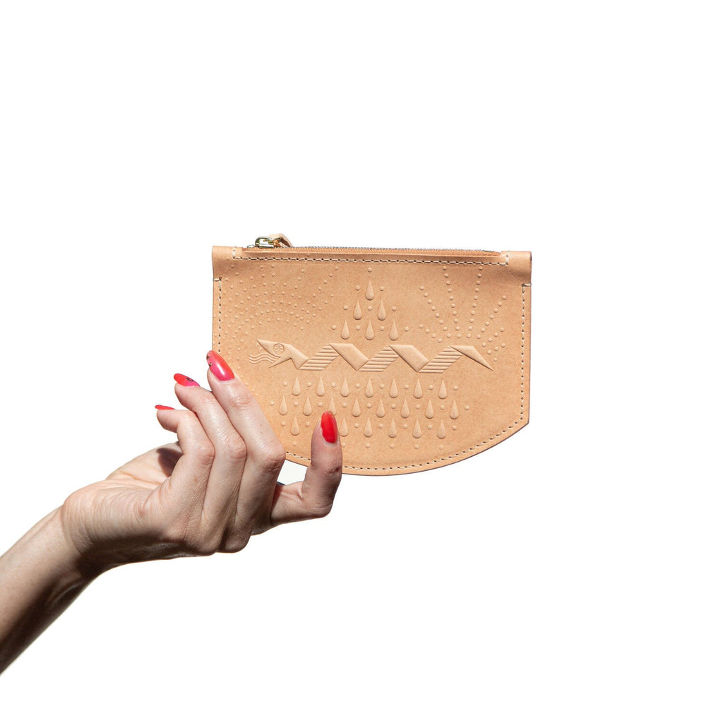 Tan leather zippered coin pouch with hand stamped snake design, shown in hand