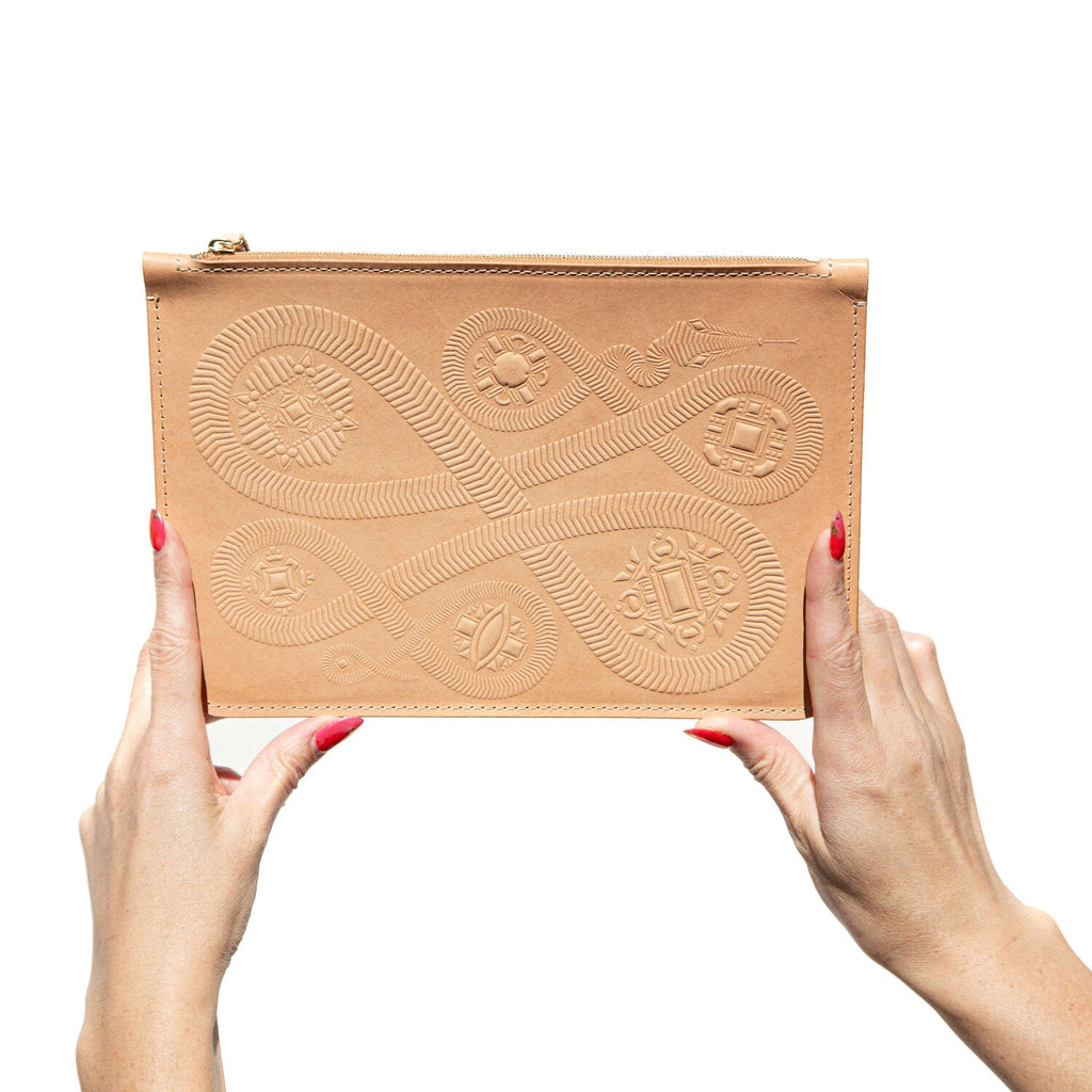 Large tan leather zippered pouch hand stamped with snake design, shown in hands