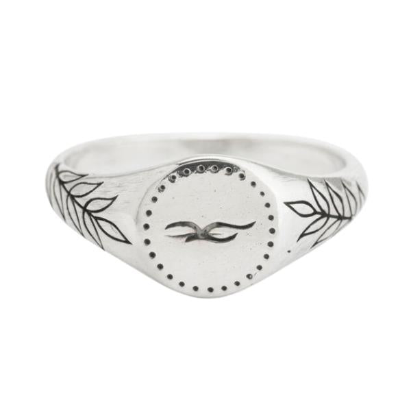 A petite silver signet ring engraved with a bird on the face and olive branches on the sides.