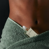 Person holding a small bottle of perfume wrapped in a green towel