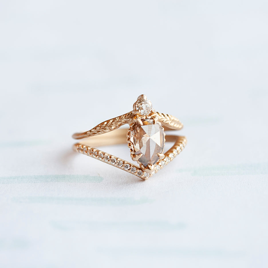 A yellow gold pointed contour wedding band set with a single row of tiny pave diamonds. With an engagement ring.