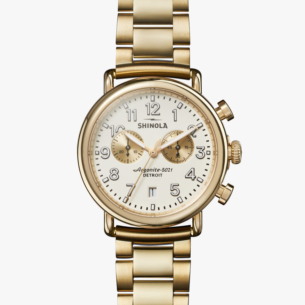 wide gold metal link bracelet watch, round white face with white hands