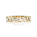 A yellow gold and diamond eternity band with bezel set emerald cut diamonds set vertically all the way around.