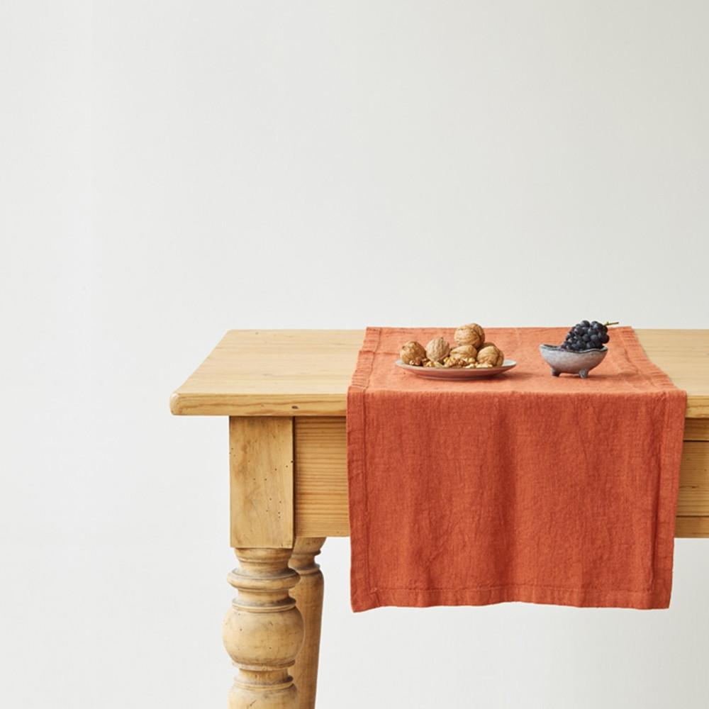Linen Tales red orange table runner on a table with fruit, front view
