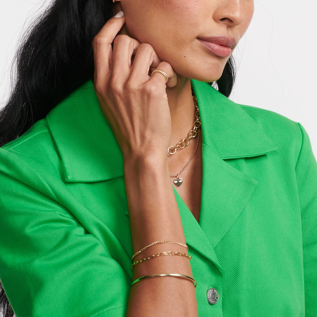 A classic gold chain bracelet made up of petite oval wire links. On model.