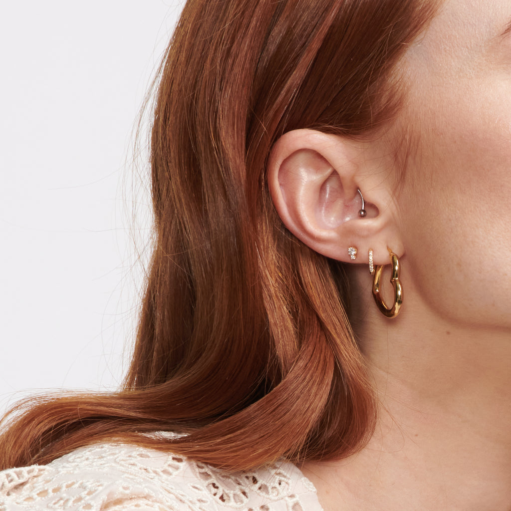 Puffed heart shape gold hoop earrings. on model.