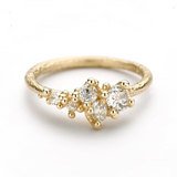 A tapering cluster of antique cut white diamonds all nestled amongst polished granules of rich yellow gold on a textured band.