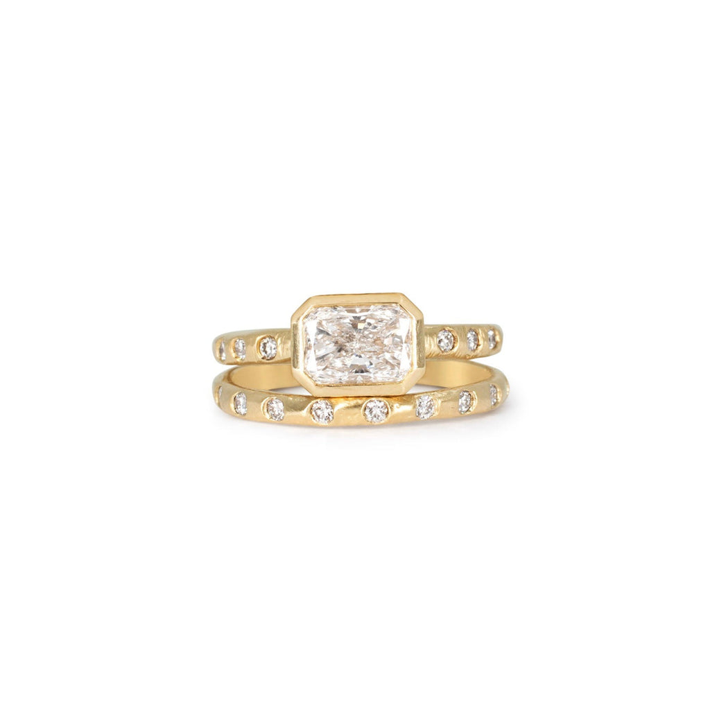 A textured yellow gold wedding band with flush set diamonds all the way around. Paired with a matching engagement ring.