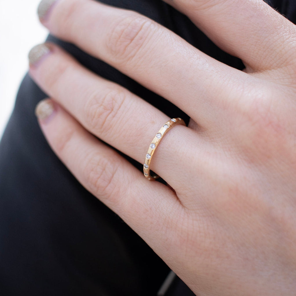 A textured yellow gold wedding band with flush set diamonds all the way around. On hand.