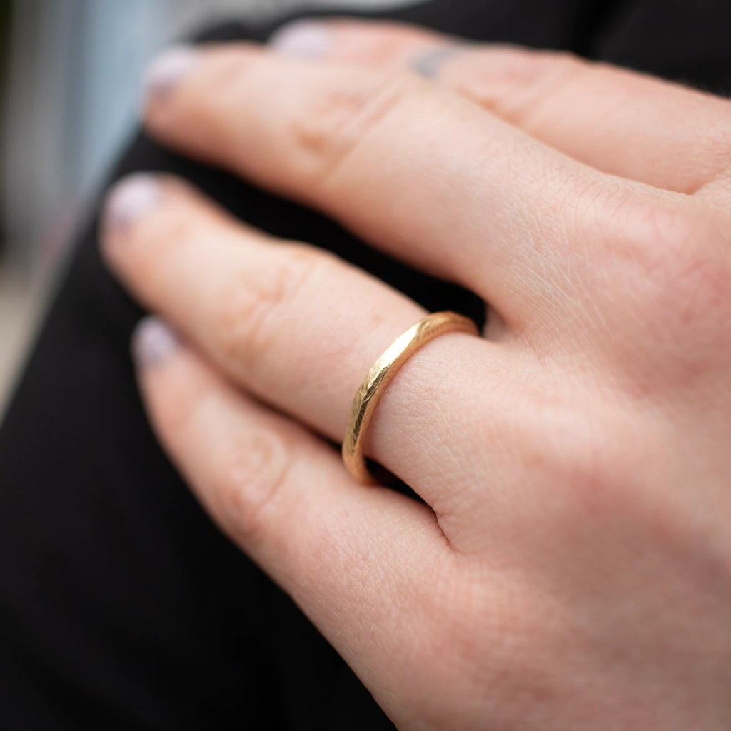 Page Sargisson gold thick wedding band on model, top view