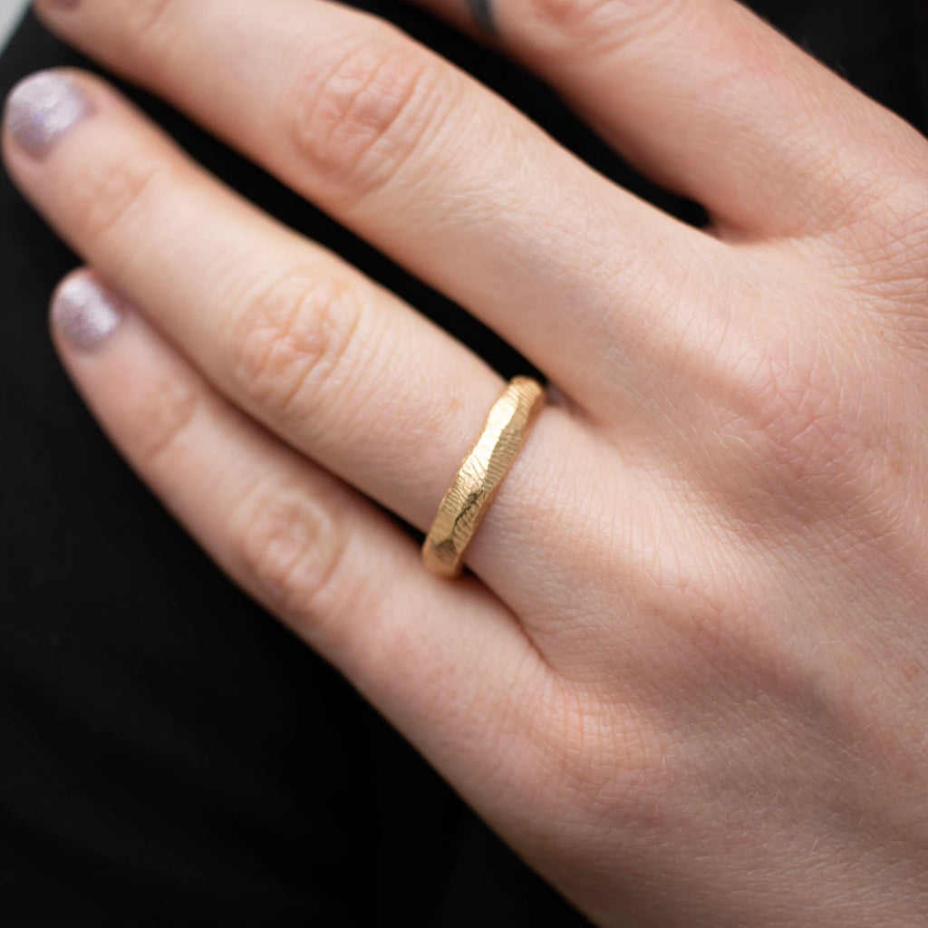 Page Sargisson thick gold wedding band on model, top view