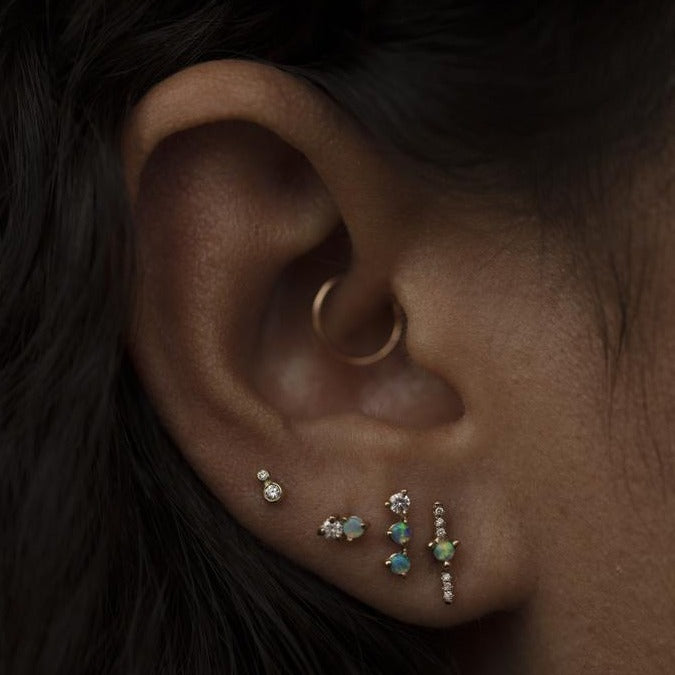 Wwake gold stud earring with 2 opals and 1 diamond on model, front view