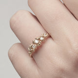 Unique diamond cluster engagement ring with golden granules, on a gently textured band.