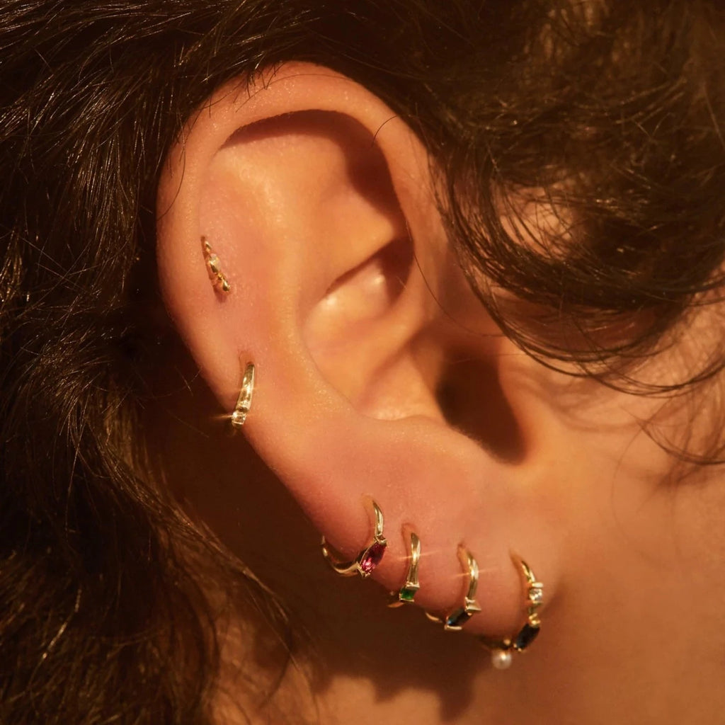 Pamela Love gold huggie earring with opal, turquoise and ruby, on model, front view