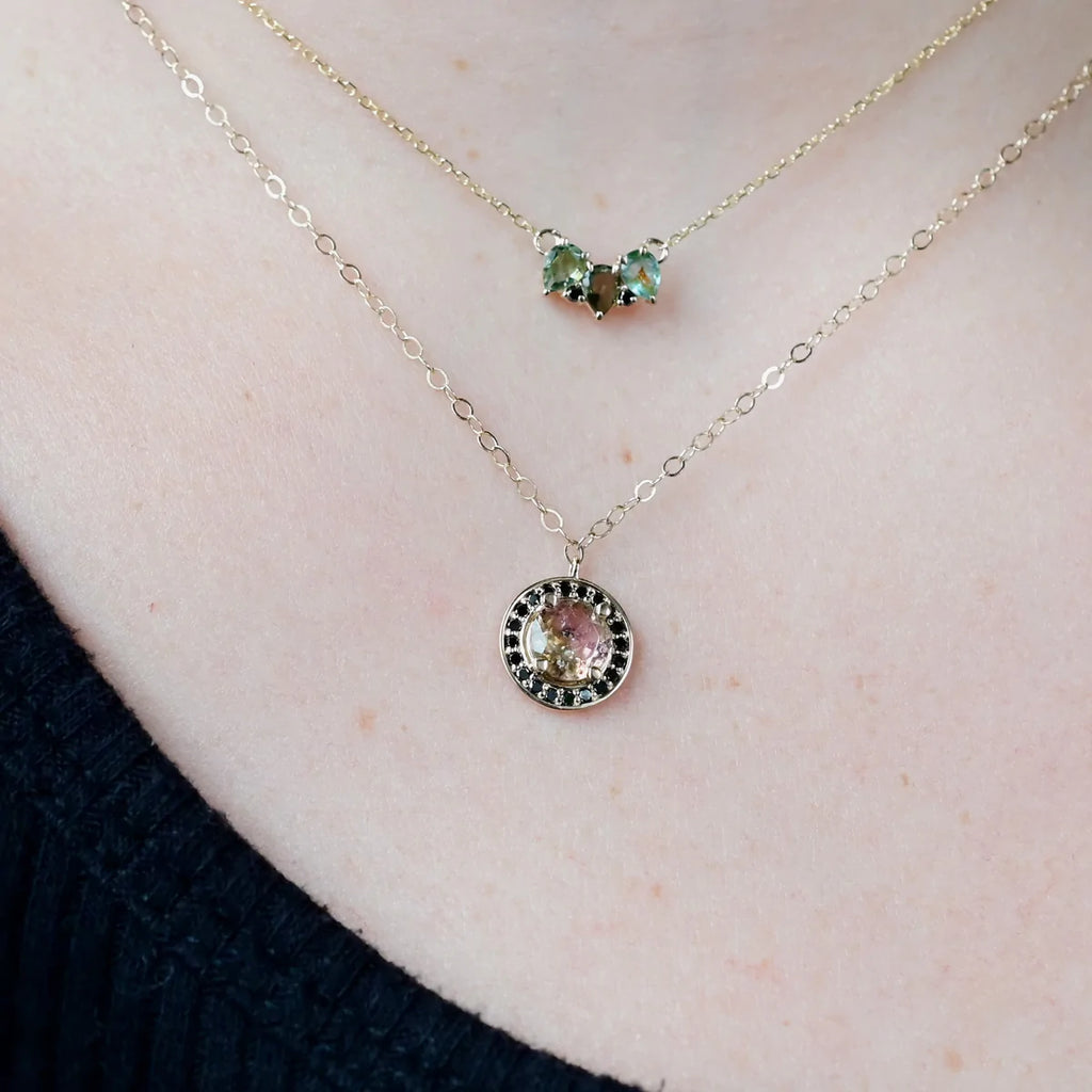 Miaranted gold necklace with green tourmaline and black diamond on model, front view