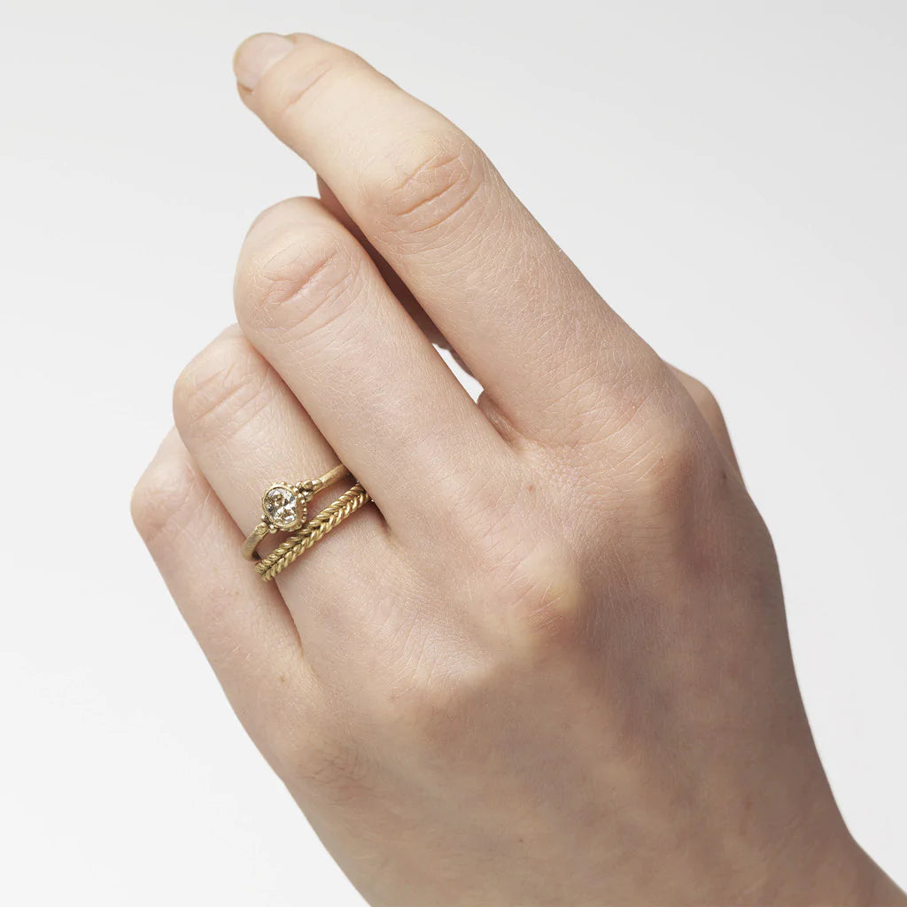A yellow gold band featuring a woven rope pattern. On hand.