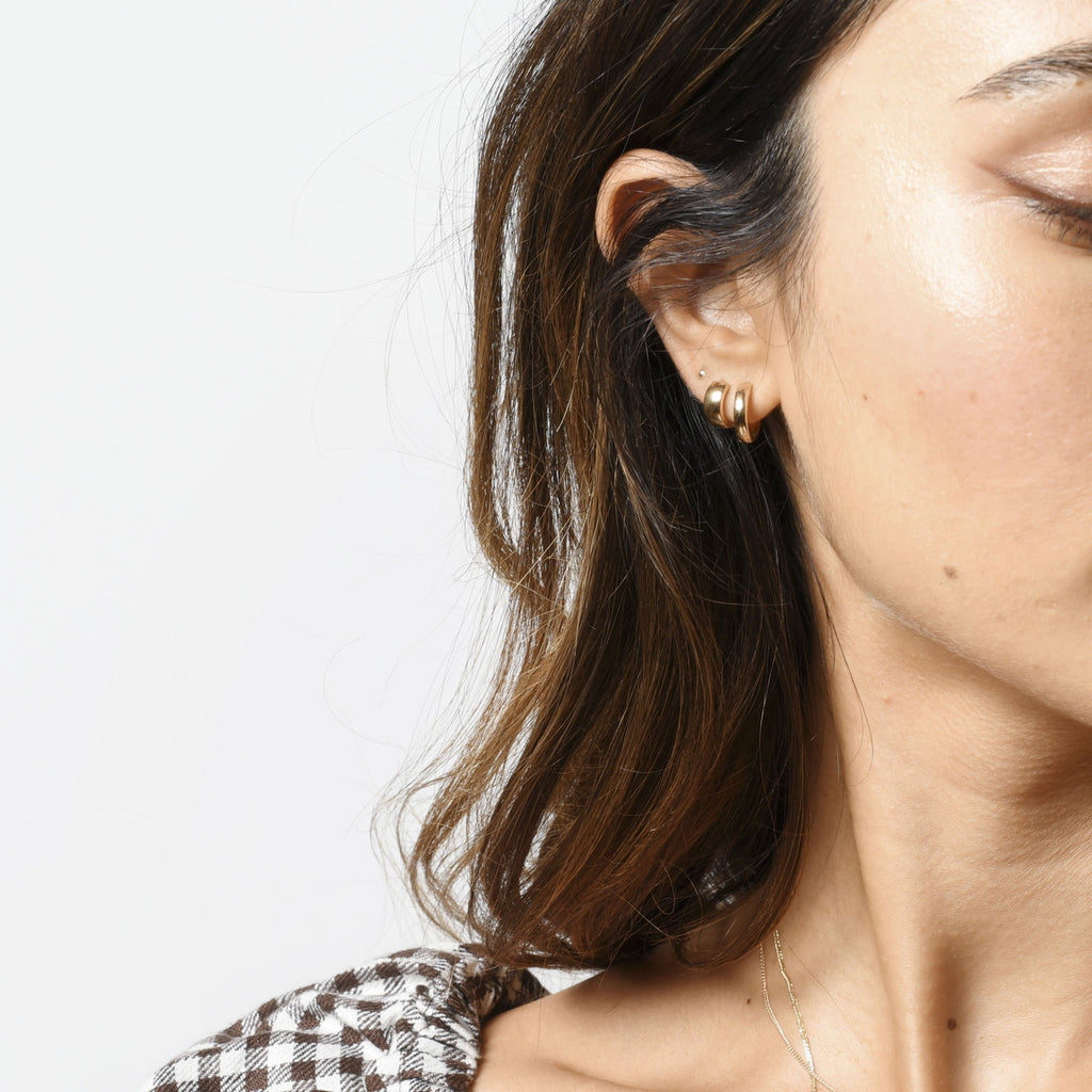 A small, wide gold hoop earring. On ear.