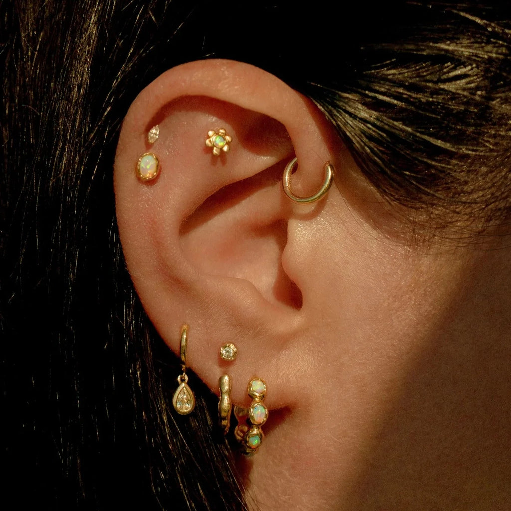 Pamela Love gold huggie earrings with opals, on model front view