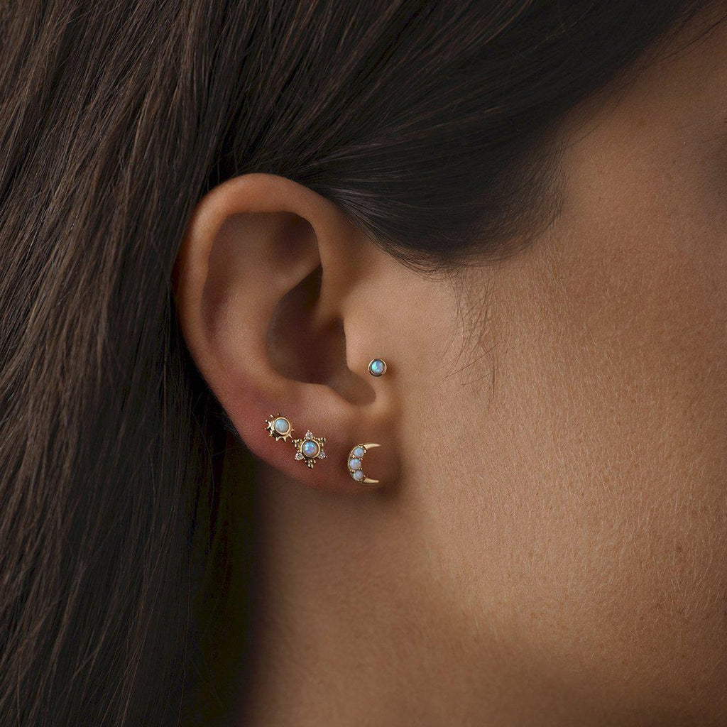 Pamela Love gold crescent moon stud earring with opals, on model, front view