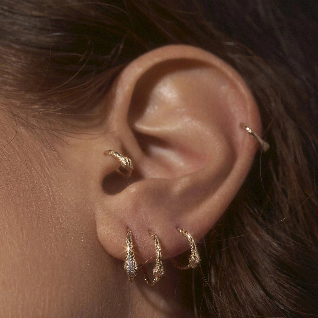 Pamela Love gold huggie earring with snake detail on model, front view