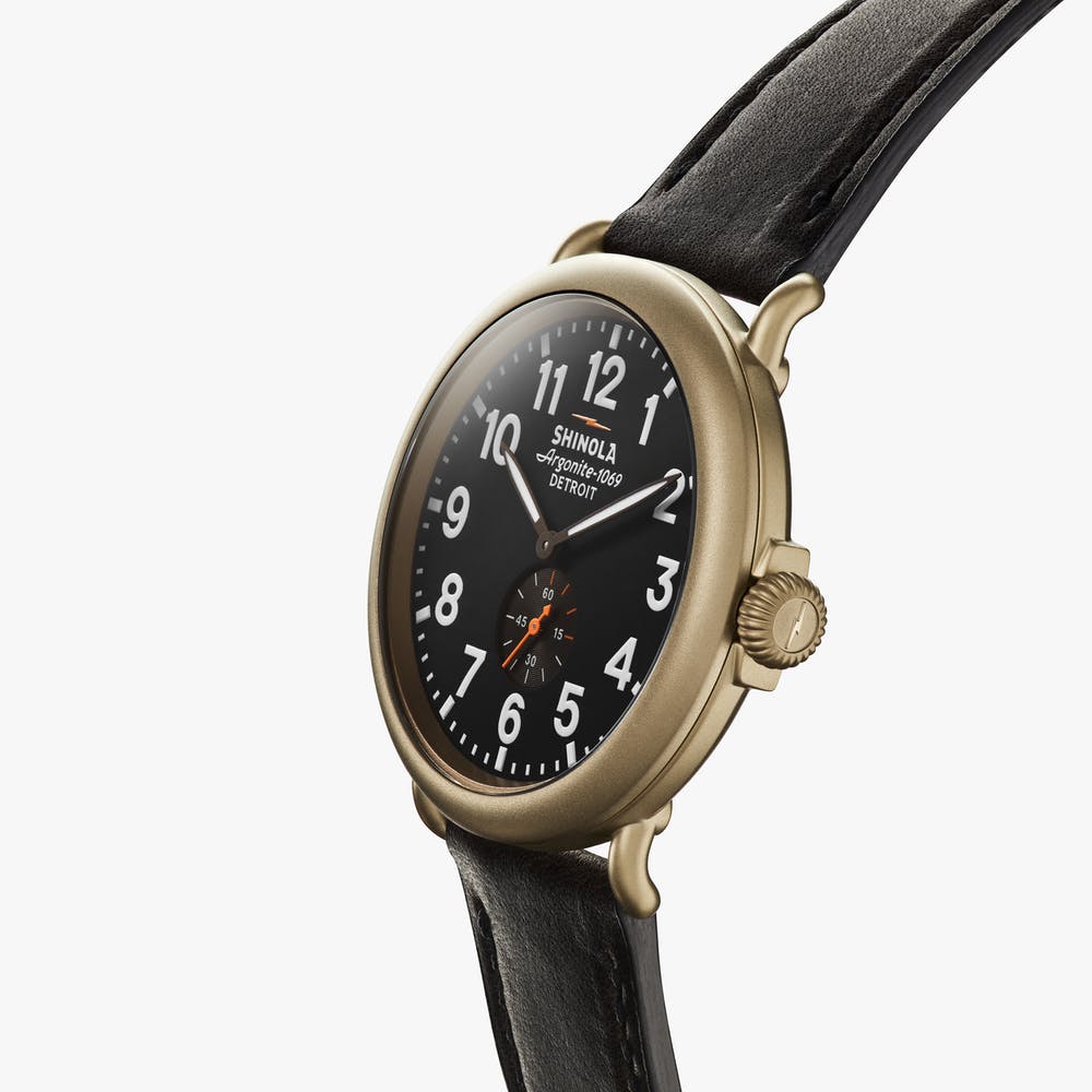 Shinola black watch face gold case with black leather strap, angled front view