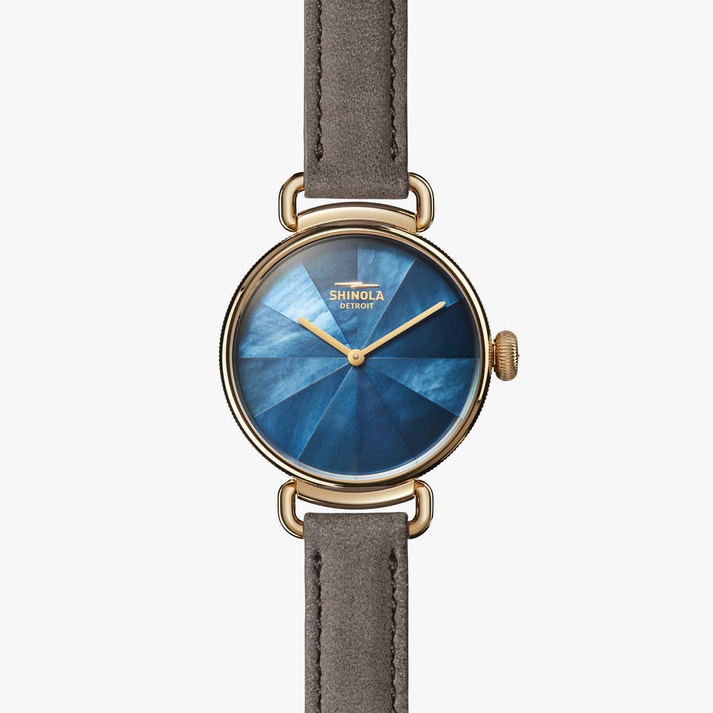 Shinola gold watch with blue face and gray strap, front view