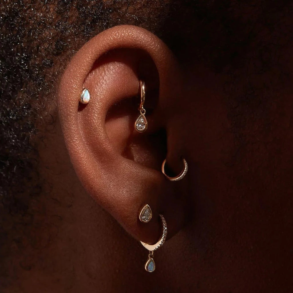 Pamela Love gold huggie earrings with diamonds and opal drop, on model side view