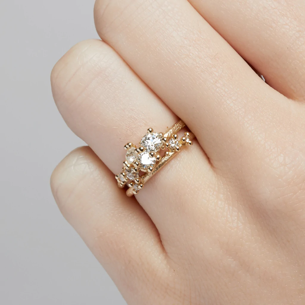 A tapering cluster of antique cut white diamonds all nestled amongst polished granules of rich yellow gold on a textured band.