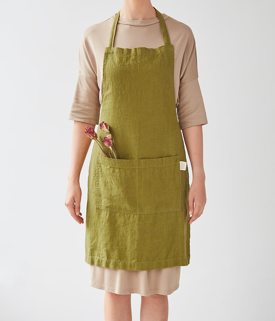 Linen Tales green apron on model, front view