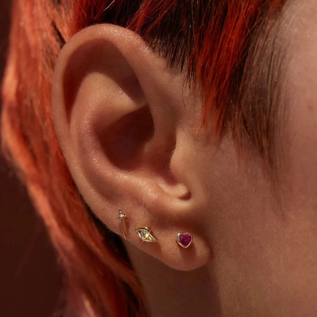 Pamela Love gold heart stud earrings with ruby, on model front view