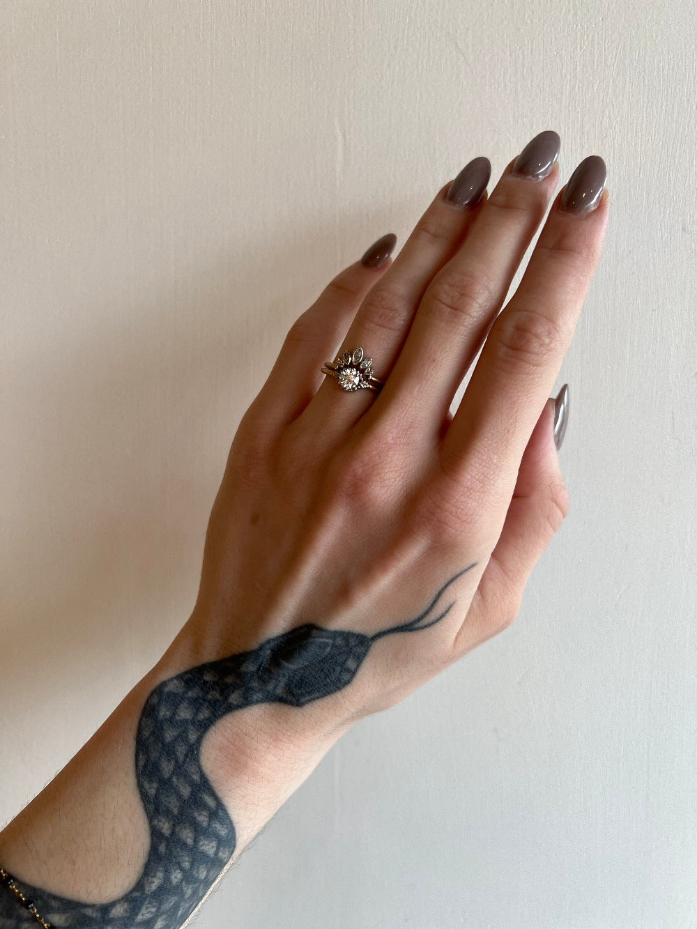 A diamond contour ring crafted with a slim yellow gold band. Three marquise diamonds are bezel set into white gold with a curved outline and delicate leaf details. On hand.