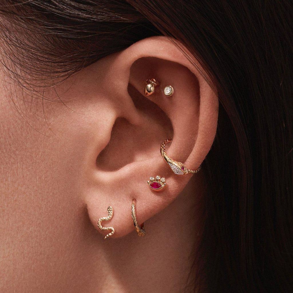 Pamela Love gold eye shaped stud earring with ruby and diamonds, on model, front view