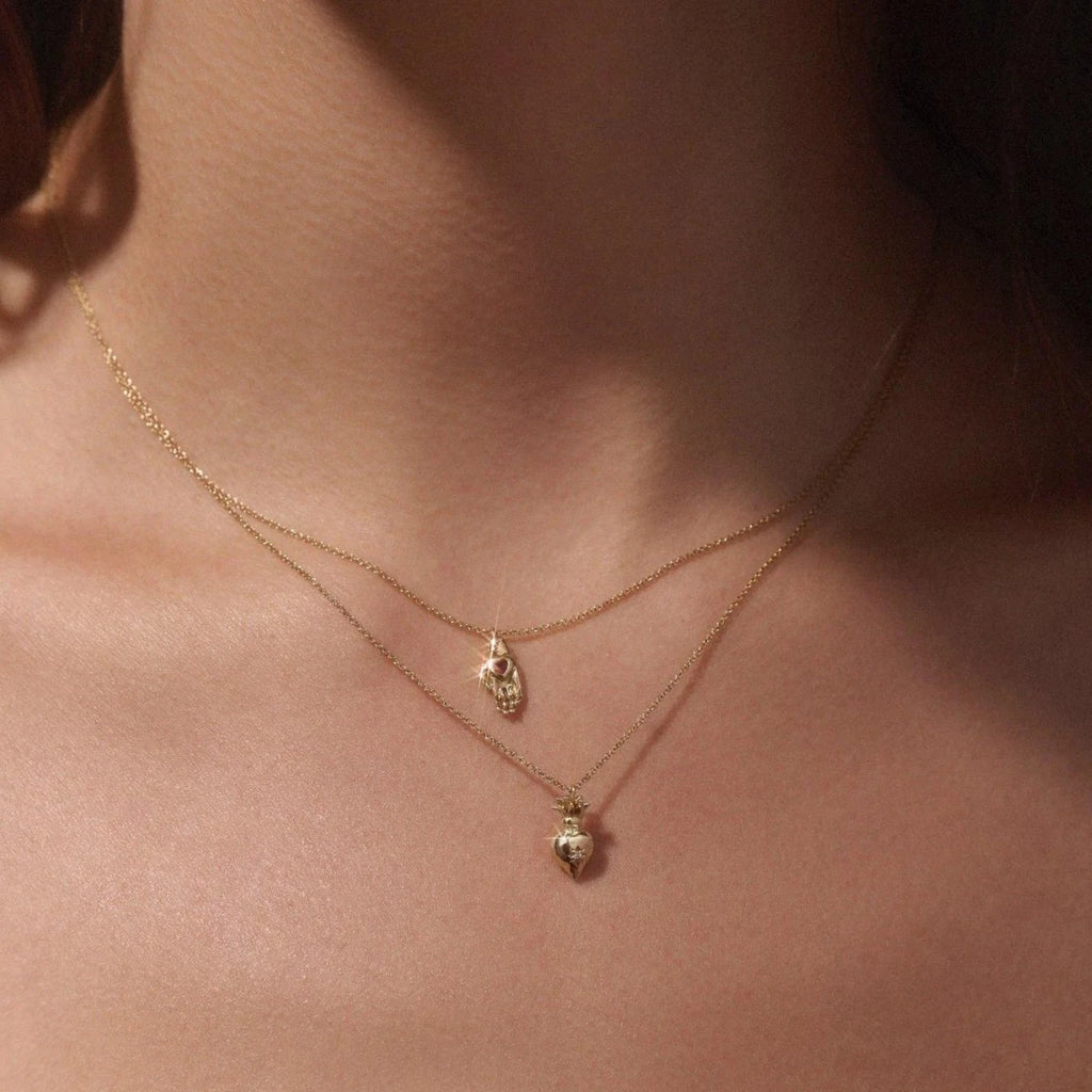 Pamela Love gold necklace with hand shaped pendant and ruby, on model, front view