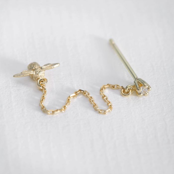 Alex Monroe gold stud earring with long chain, diamonds, and bee pendant, top view