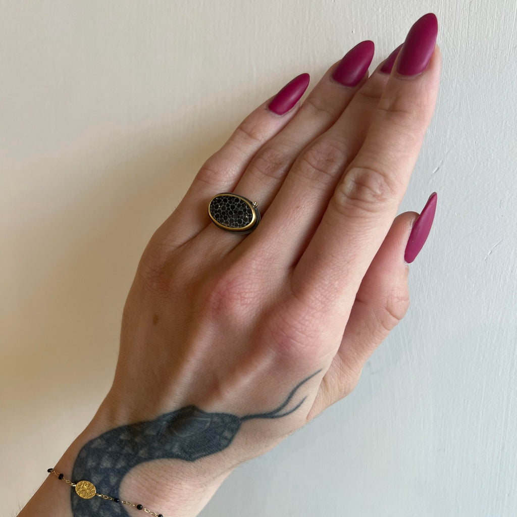 Ananda Khalsa silver ring with black fossil, gold, and diamonds on model, top view