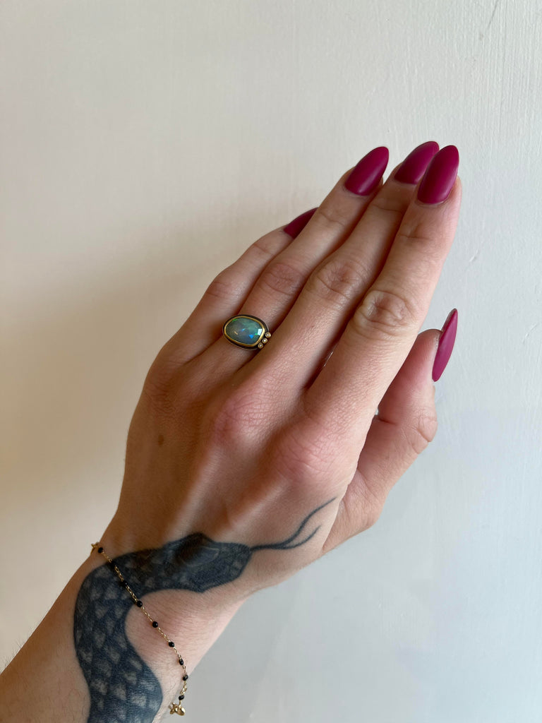 Ananda Khalsa silver ring with opal, gold, and 3 diamonds, on model, front view